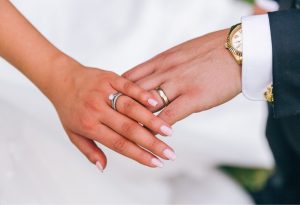a bride and groom having their wedding bands and engagement ring on their fingers, How to Wear an Engagement Ring and Wedding Band